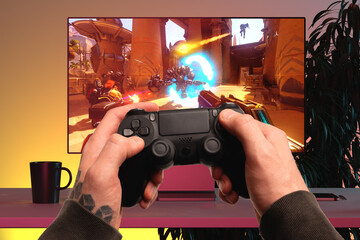 Close up of Man Hands Holding Wireless Joysticks On Foreground. Modern TV Set With Shooter Video Game On Background. 3d rendering