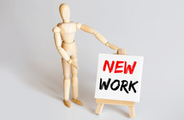 Wooden man shows with a hand to white easel with text NEW WORK on white background