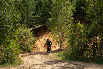 Outfitted biker on off-road motorcycle riding through abandoned sand quarry, extreme hobby. Motocross.