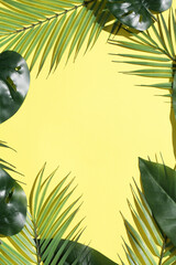 Fototapeta na wymiar Creative layout from tropical leaves and palms on bright yellow background with deep shadows. Minimal summer concept. copy space. flat lay