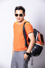 Portrait young handsome man in a blank orange t-shirt wearing sunglasses with backpacker on white background.