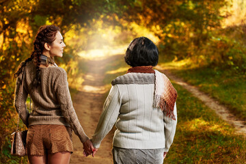 Happy mother and daughter spending time together and walking in forest