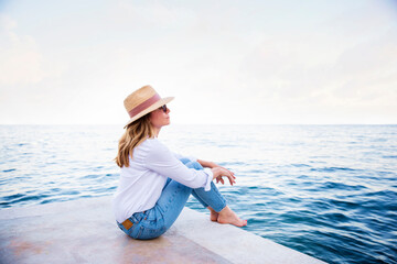 Woman sitting on cliff and relaxing by the sea