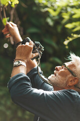 An active hobby in retirement. Close-up portrait, man photographing nature.