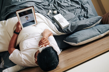 Sick man spending day in bed and video calling his doctor to