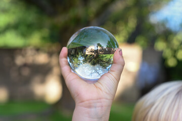 a boy holds a glass ball with reflection of a tree as an environmental conservation concept