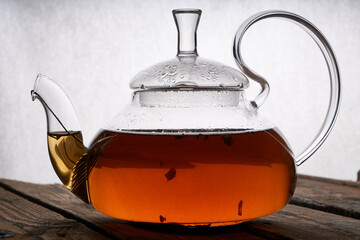 teapot with brewed hot tea on a wooden, cozy background