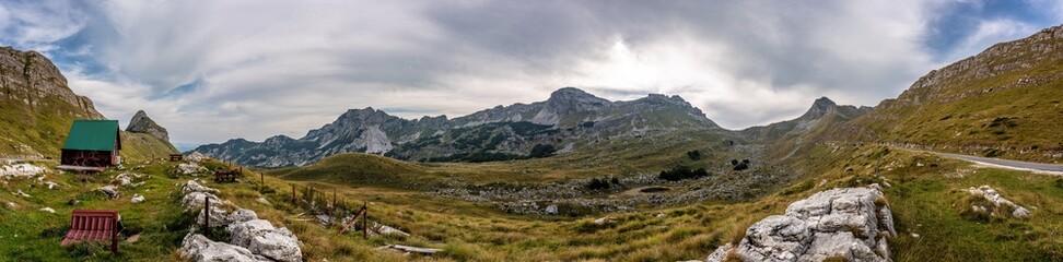 Beautiful panorama on top of Durmitor mountain. Tiny house with benches and unbelievable view to mountains of Montenegro. Lovely sky with clouds.