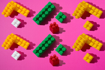 A pattern of green, white, red and yellow constructor details on a pink background