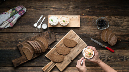 Woman preparing vegan sandwiches on a wooden table, top view