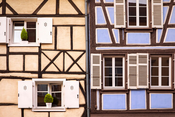 Old fashioned half timbered facades, cute small windows with shutters. Rustic elevation. French traditional architecture, detail close-up. Alsace, Colmar, France.