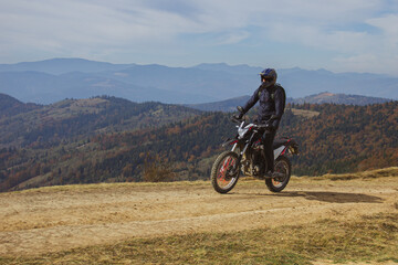 A man in motorcycle protection and helmet riding his motorcycle bike in the highland dusty off-road, mountain biking