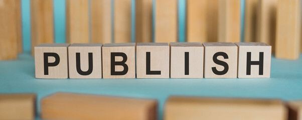 Wooden cube with word Publish on a light blue background. Concept image