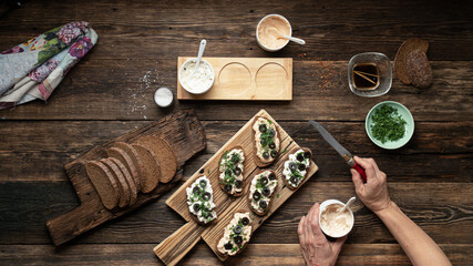 Woman preparing vegan sandwiches on a wooden table, top view