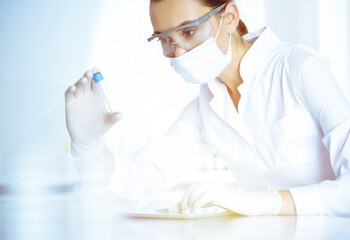 Fototapeta premium Female laboratory assistant analyzing a blood sample at hospital. Medicine, health care and researching concept