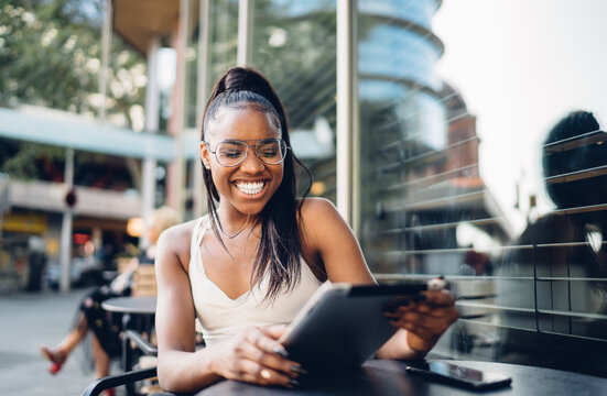 Happy pretty dark skinned woman satisfied with good news from social media checking mail on digital tablet,funny african american female millennial blogger laughing at content 