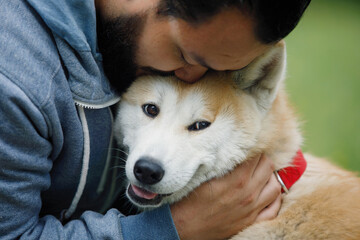 Guy with red akita dog on green grass.