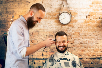 Good looking man visiting barber shop. The barber cuts his hair and trims his beard.