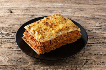 Piece of meat lasagna on black plate on rustic wooden table	