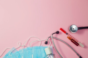 Pills, stethoscope and medical masks on pink background