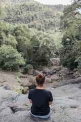 Naklejka premium girl sits on a stone in the forest.
