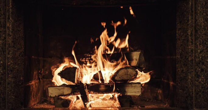 Slow motion of Fireplace burning. Warm cozy fire in a brick fireplace close up. Cozy winter relax background. Christmas mood. Filmed in RAW 120fps 4k DCi.	