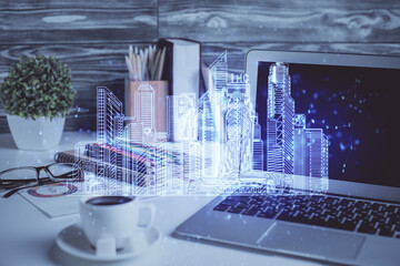 Desktop computer background in office and big town buildings hologram drawing. Double exposure. Smart city concept.