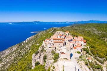Fototapeta na wymiar Aerial view of small historical town of Lubenice on the high cliff, Cres island in Croatia, Adriatic sea in background