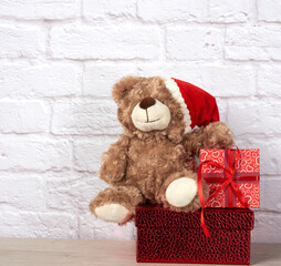 teddy bear in santa claus hat and box tied with red ribbon