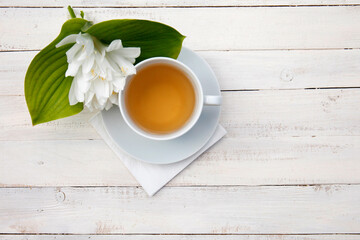 Fototapeta na wymiar teacup with bouquet of fresh white hosta flowers on white wooden table