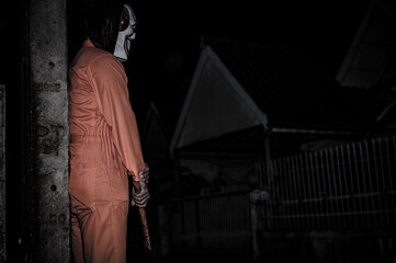 Fototapeta na wymiar Asian handsome man wear clown mask with weapon at the night scene,Halloween festival concept,Horror scary photo of a killer in orange cloth