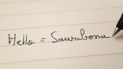 Beginner Zulu language learner writing Hello word Sawubona for homework on a notebook