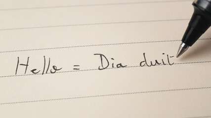 Beginner Irish Gaelic language learner writing Hello word Dia duit for homework on a notebook - obrazy, fototapety, plakaty