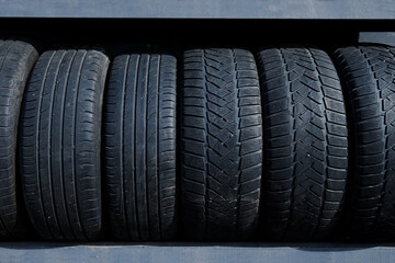 Stack of used tires at the car service waiting for disposal. Worn out rubber tires at the car tire fitting station. Waste recycling. 