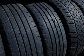 Stack of used tires at the car service waiting for disposal. Worn out rubber tires at the car tire fitting station. Waste recycling.  Tire closeup.