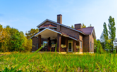 exterior of a two-story country house made of brown brick with a mansard roof