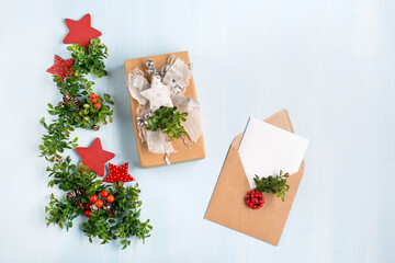 Rustic wooden blue background with Christmas gift and empty white card in craft envelope.