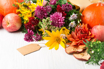 Autumn bouquet of yellow and pink flowers on white wooden background.