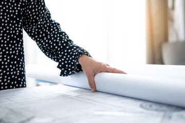 Engineer woman hand with blueprint on desk.