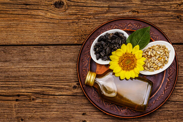 Sunflower oil in glass cruet with flower head and seeds in wooden bowl