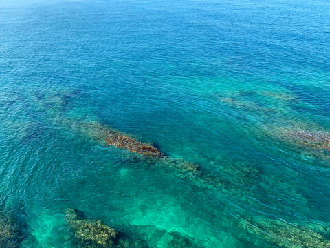 View of a coral reef. Turquoise sea water. Calm ocean. Mediterranean coast. Rocky beach