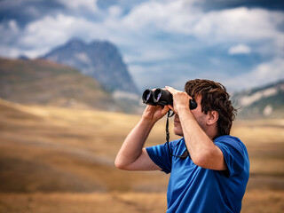 Hiker with binoculars observes birds in the mountains