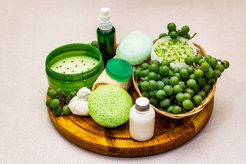 Obraz na płótnie Canvas Natural spa accessories and green grapes placed on a wooden plate