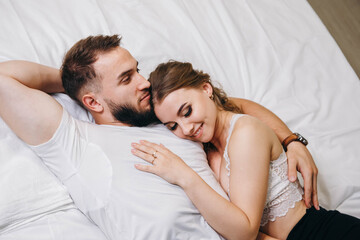 Beautiful couple kissing in bed. Young happy family lying together