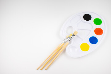 The palette of paints on a white background with brushes. Fine art.
Copyspace.
flat lay