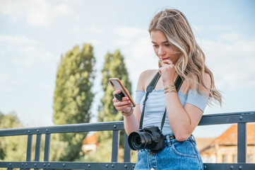 Tourist woman with her camera and using her smartphone