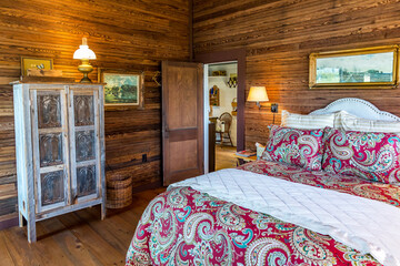 Rustic cabin bedroom with a large bed, quilt and wood-paneled walls and ceiling