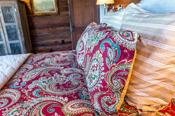 Rustic cabin bedroom with a large bed, quilt and wood-paneled walls and ceiling