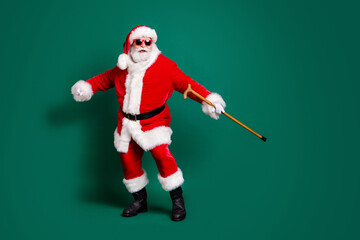 Full length body size view of his he nice attractive cheerful cheery Santa holding in hand cane having fun dancing enjoying rest celebration festal day Eve Noel isolated over green color background