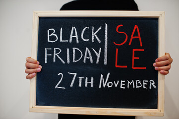 Sale 27th November written on blackboard. Black friday concept. Boy hold board.